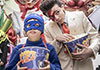 Gio im superhelden-Kostüm mit einem Bottich Popcorn, dahinter Jack, ebenfalls mit Popcorn