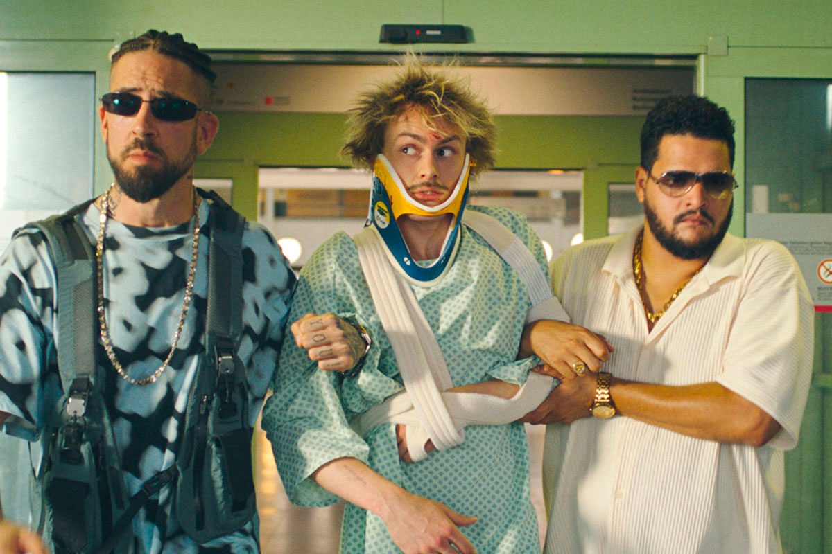 Schaaf mit Verband und Kinnstütze wird von zwei Männern mit Sonnenbrillen aus dem Krankenhaus geführt