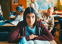 Mona sitzt an ihrem Tisch in der Klasse